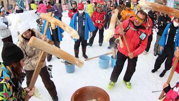 A group of people participating in a snow event, using wooden tools to interact with snow.