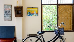 A room with a bicycle, a framed quote, and a painting. - Chan De Bua (Chanthaburi)