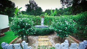 A garden with a fountain, surrounded by lush greenery and white flowers. - Chan De Bua (Chanthaburi)