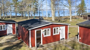 A red cabin with a door open, a window, and a chimney. - First Camp Ekudden Mariestad (Mariestad)