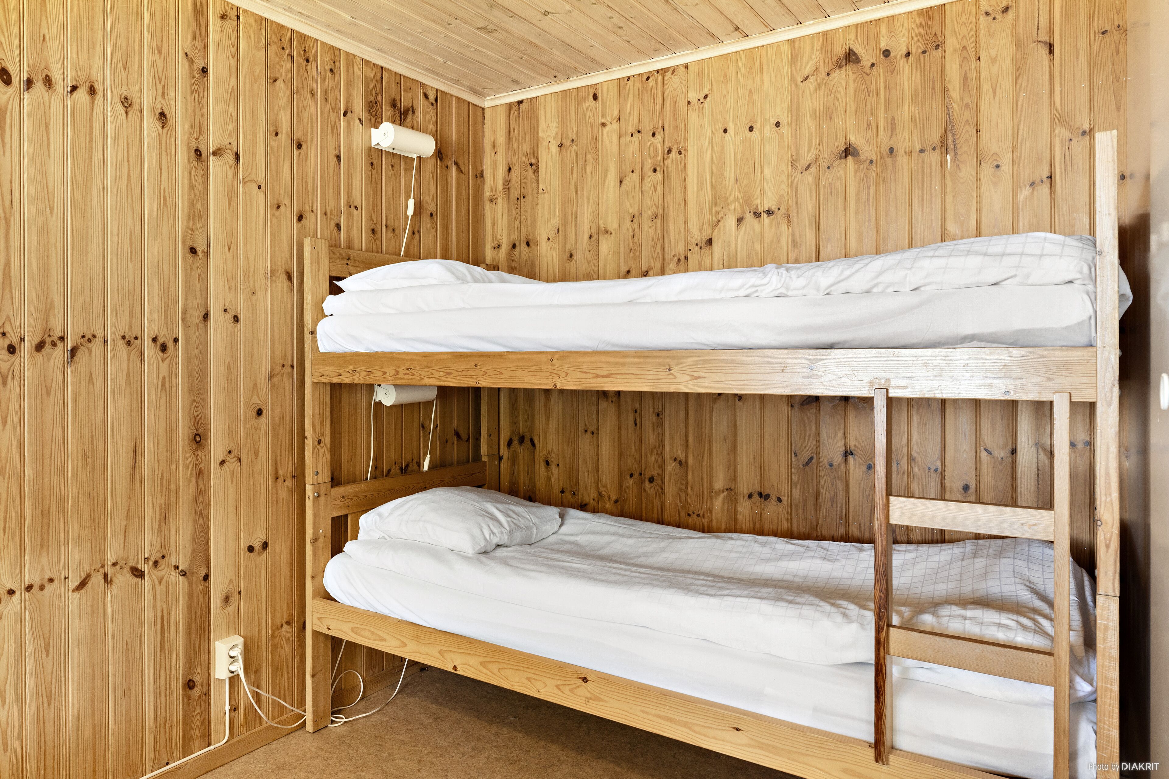 A bunk bed room with wooden walls and a white ceiling.