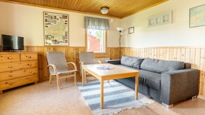 A room with a wooden ceiling, a map on the wall, a sofa, a table, a chair, a dresser, and a lamp. - First Camp Hökensås Tidaholm (Tidaholm)