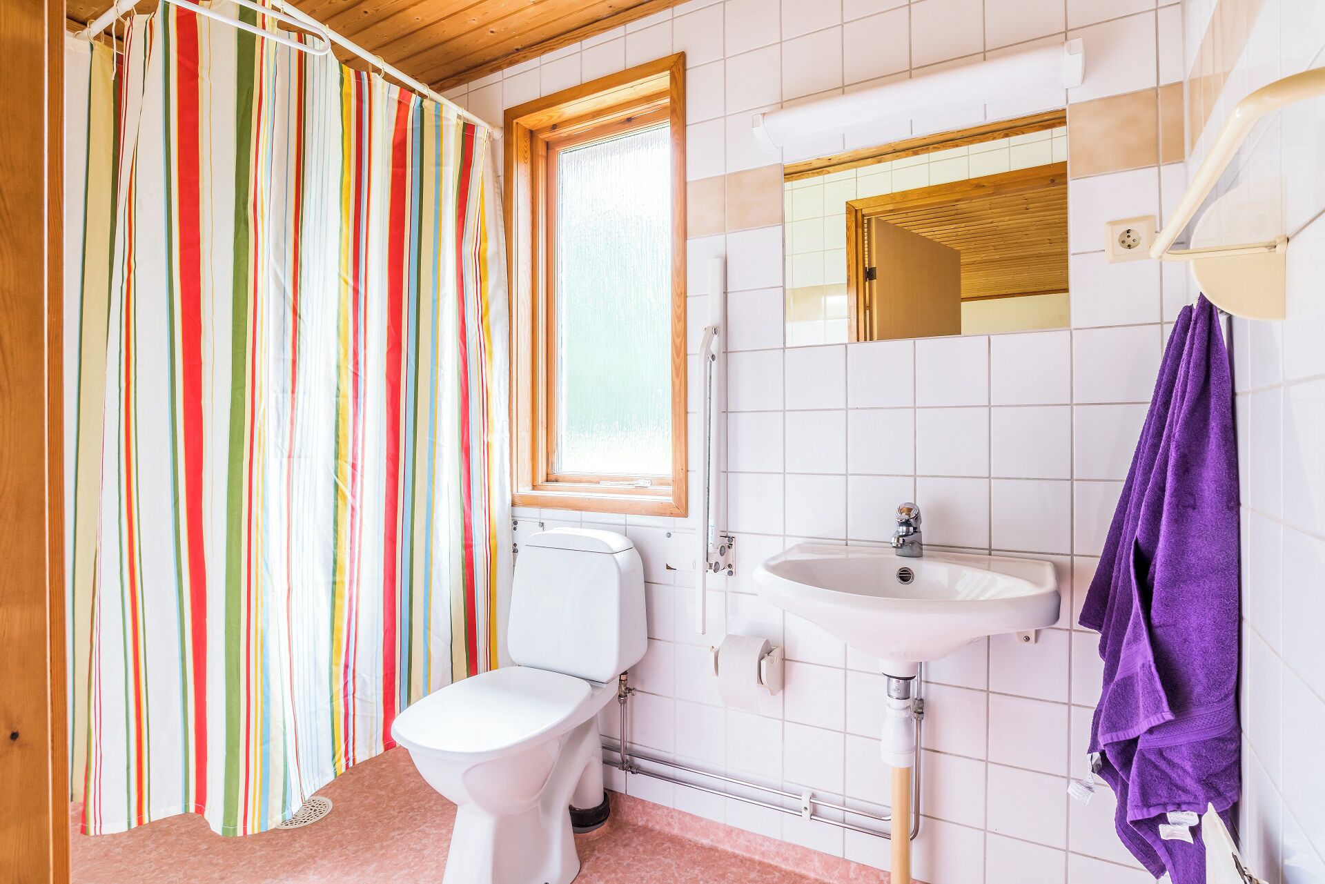 Un baño con cortina de ducha a rayas, un inodoro, un lavabo y un espejo.
