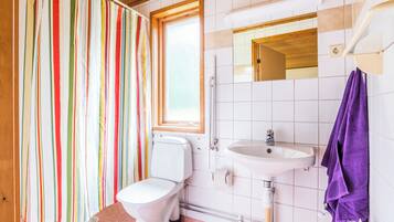 Un baño con cortina de ducha a rayas, un inodoro, un lavabo y un espejo.