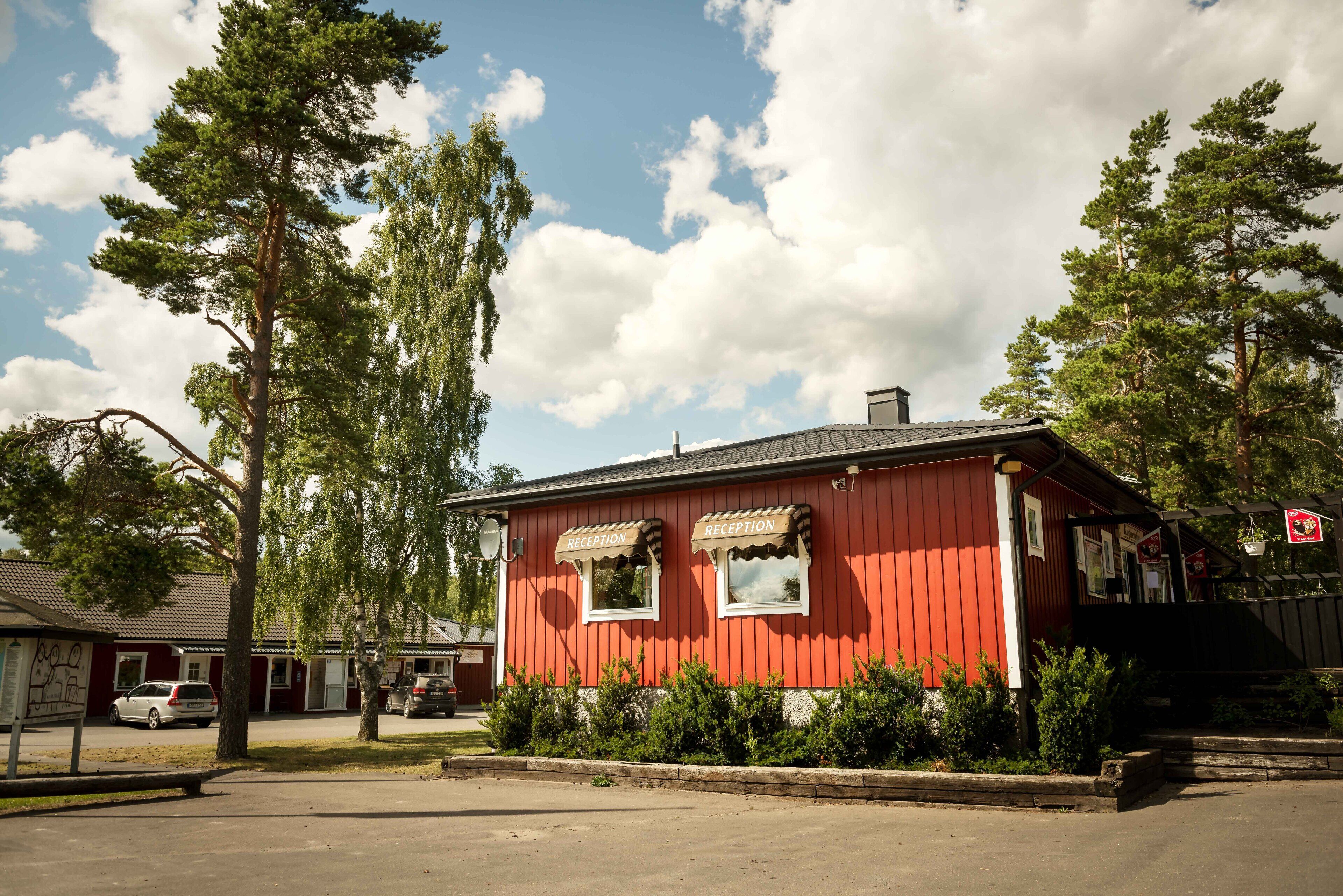 A red building with two windows labeled "Reception" and a signboard.