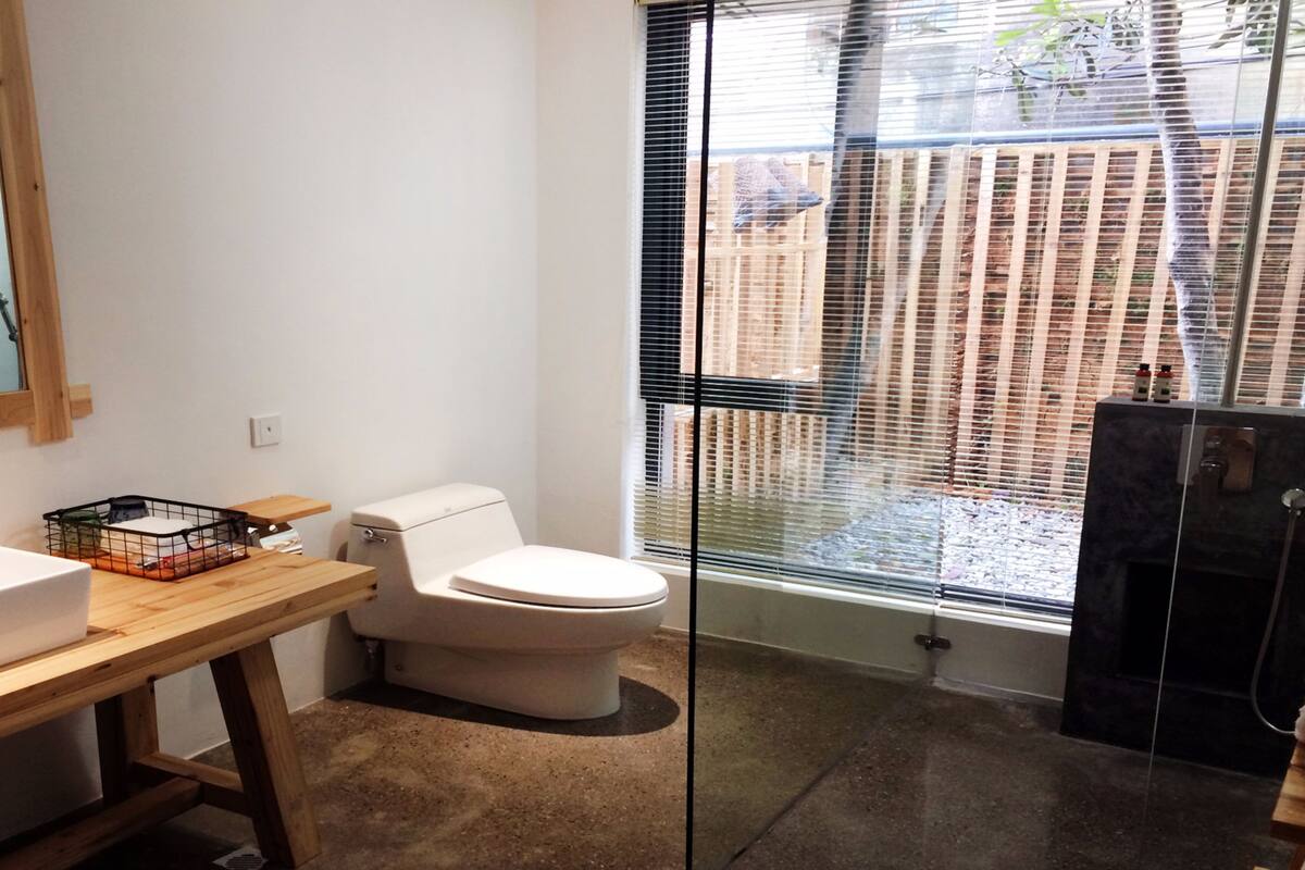 Un baño moderno con tocador de madera, inodoro blanco y cabina de ducha de vidrio.