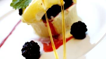 A dessert with a creamy topping, berries, and a drizzle of sauce on a white plate.