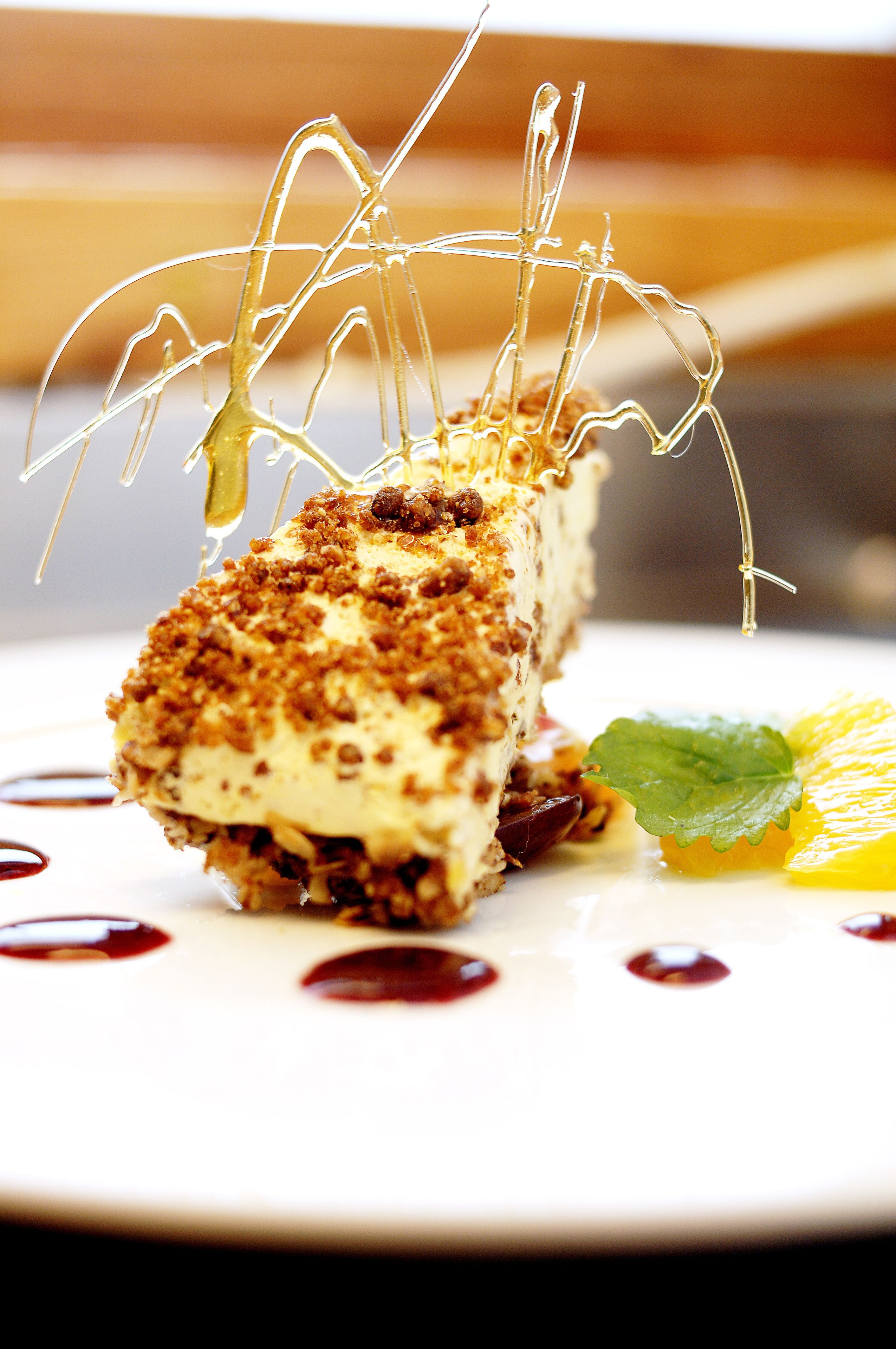 A dessert with a crispy top, a leaf garnish, and a fruit slice on a plate.