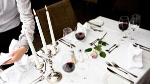 A table set for a formal dinner with white tablecloth, silverware, wine glasses, and candles. - Bryne Hotell (Time)