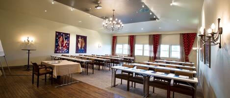 A conference room with long tables, chairs, a chandelier, and artwork on the walls.
