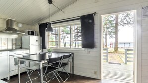 A kitchen with a dining table and chairs, a microwave, and a stove. - First Camp Mörudden Karlstad (Hammaro)