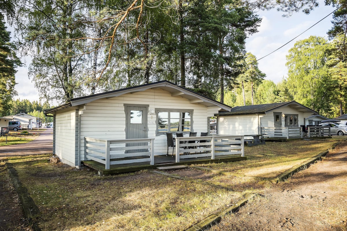 A small, single-story cabin with a porch and a covered outdoor seating area.