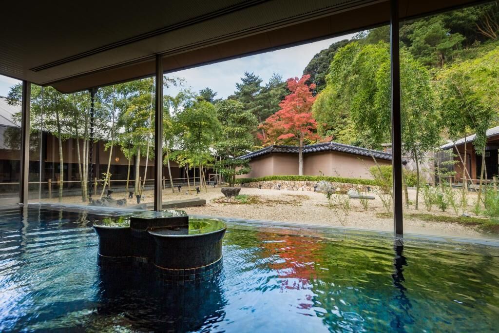 A serene indoor pool with traditional architecture and a view of a landscaped garden.