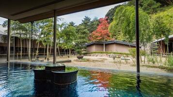 A serene indoor pool with traditional architecture and a view of a landscaped garden.