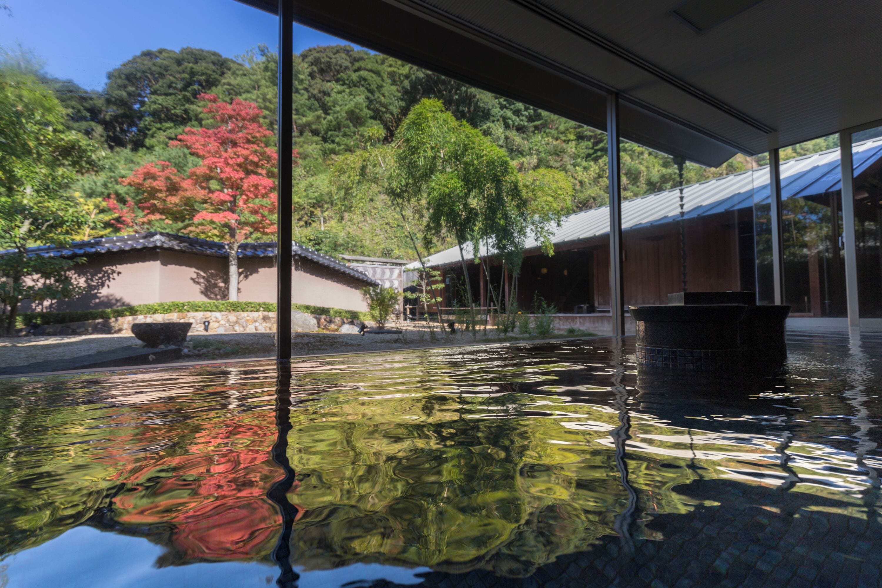 A serene indoor pond with a stone pathway and traditional architecture in the background.