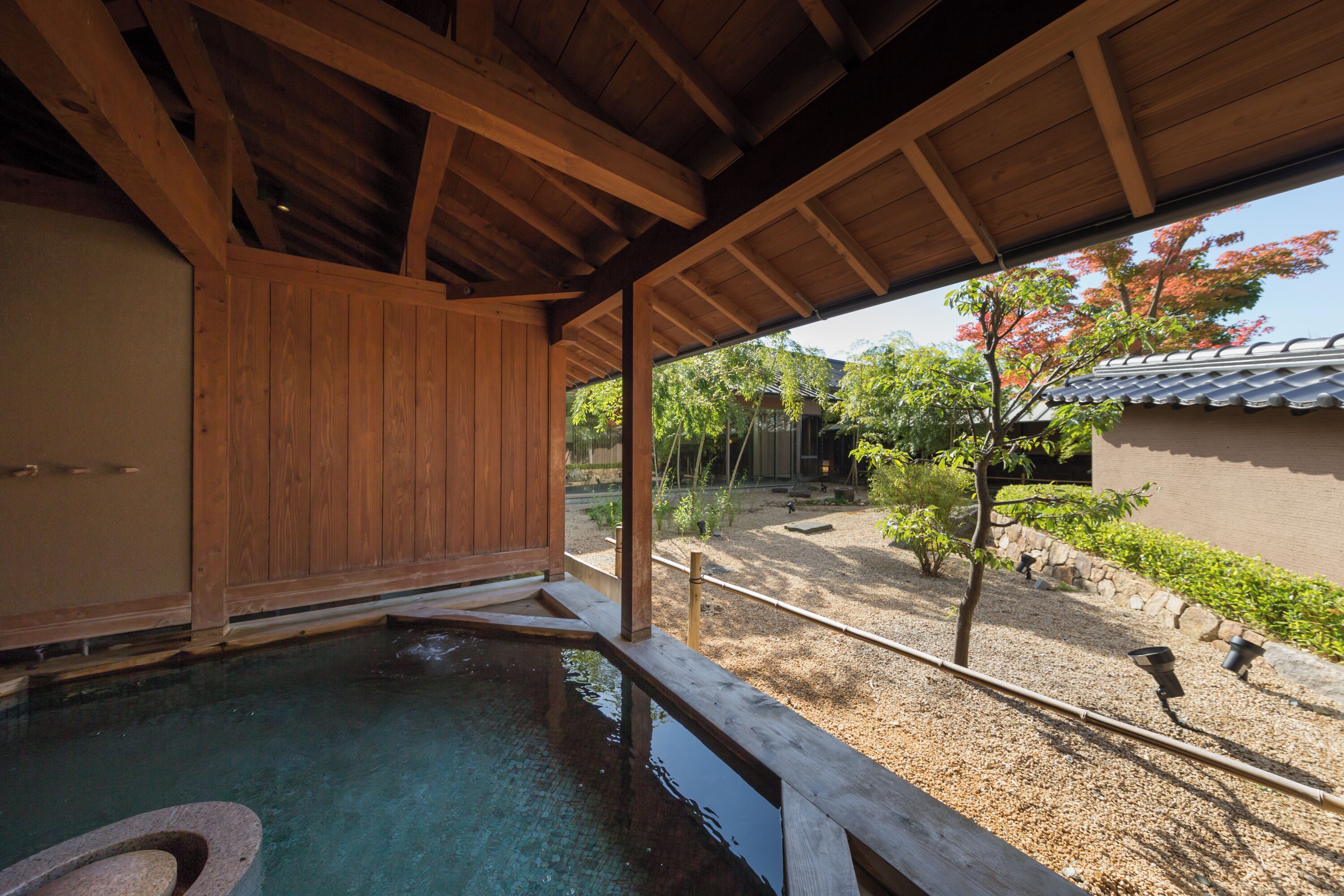 A traditional Japanese onsen with a wooden interior and a view of the garden outside.