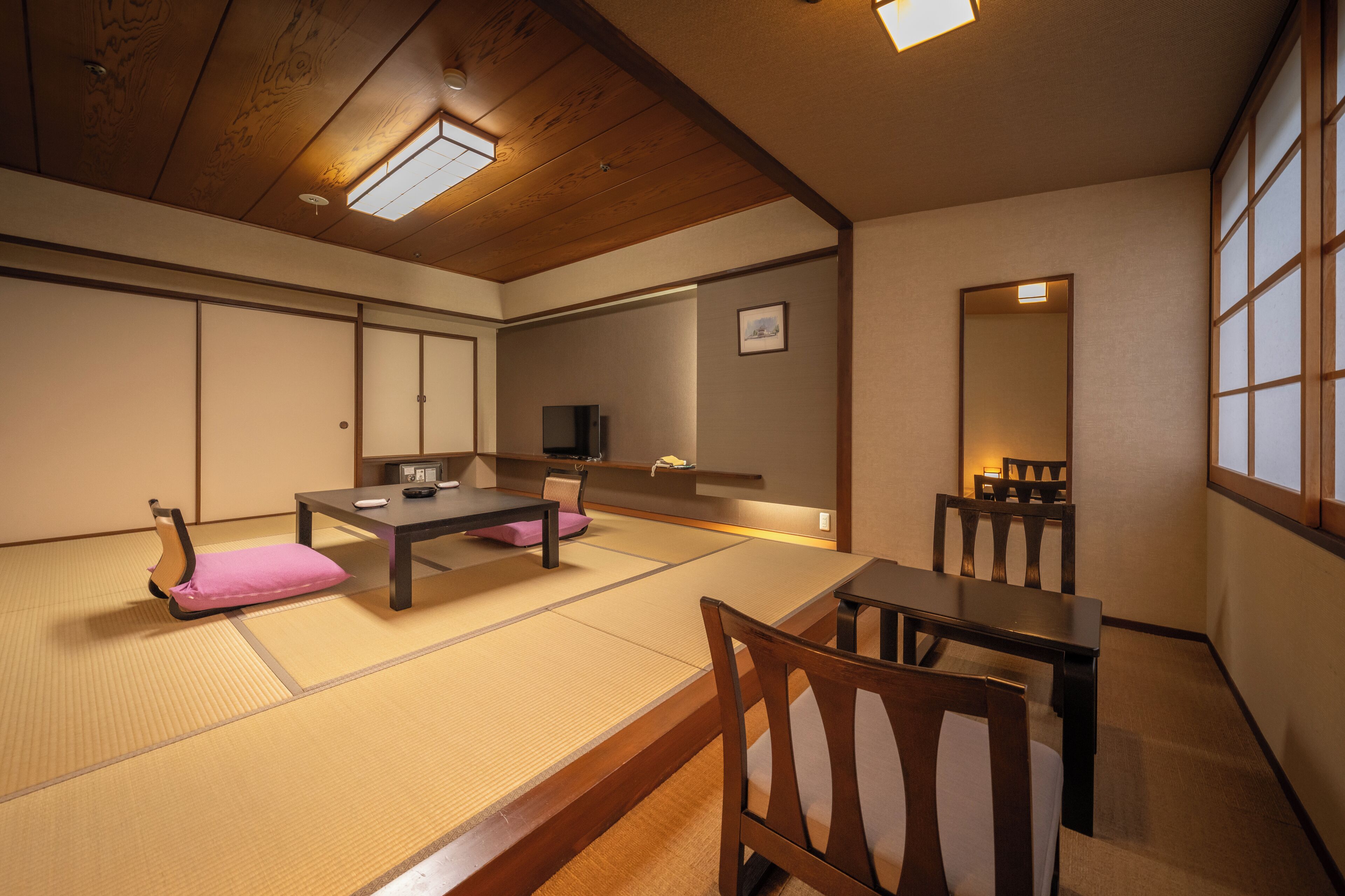 Een traditionele Japanse kamer met tatami vloerbedekking, een lage tafel en een televisie.