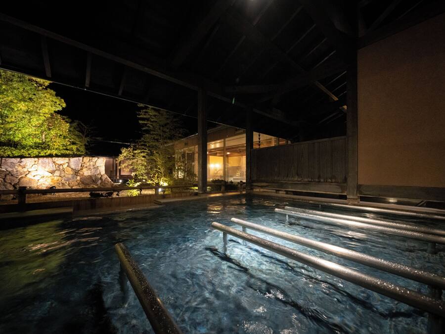 An indoor swimming pool with clear water, stone walls, and wooden beams.
