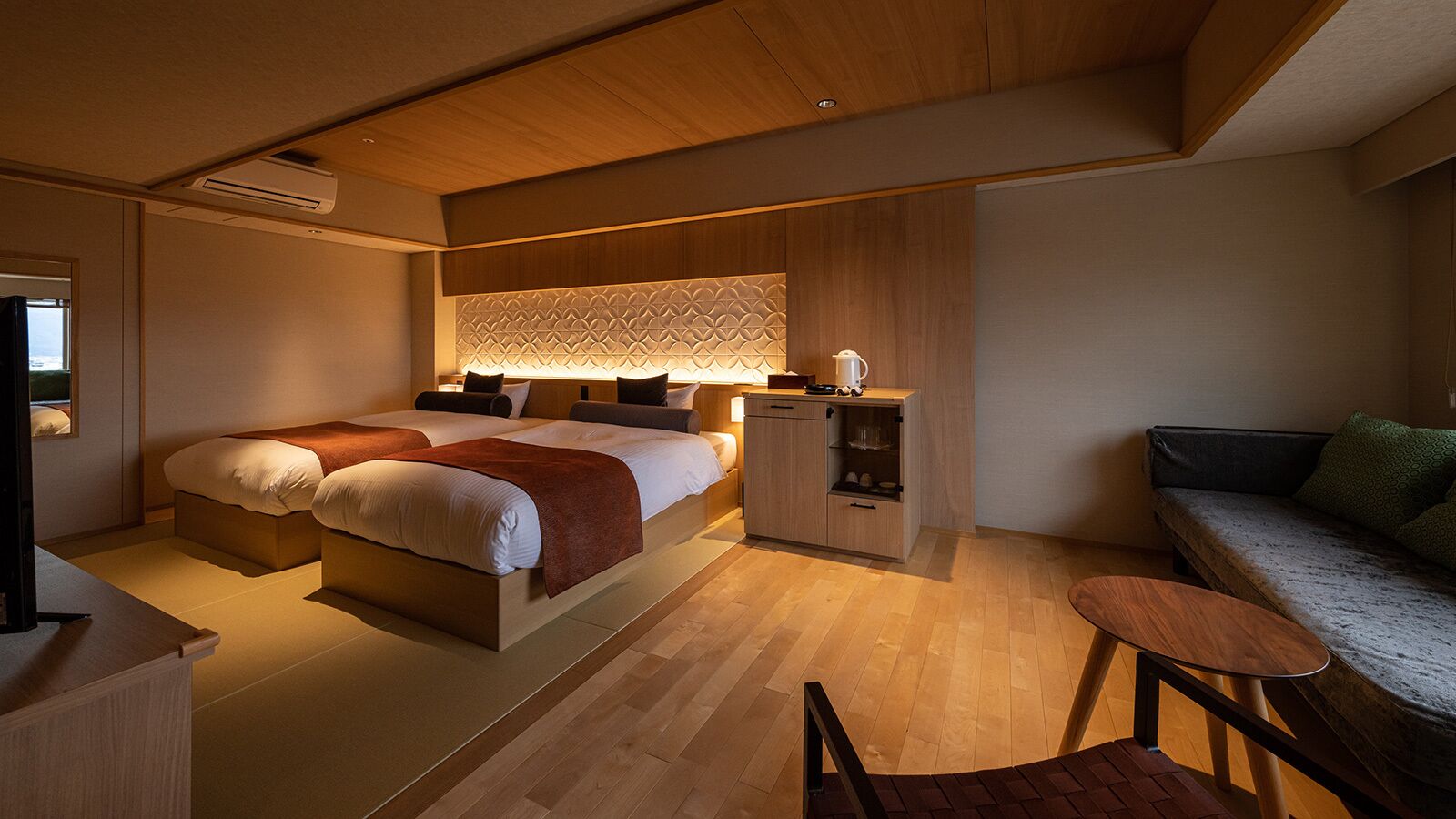 A modern bedroom with a large bed, bedside tables, a sofa, and a small table.