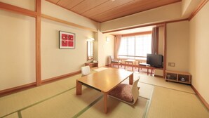 Una habitación tradicional japonesa con suelo de tatami, una mesa de madera baja y un televisor.