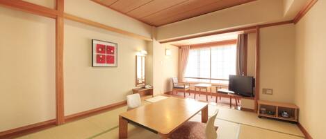 A traditional Japanese-style room with tatami flooring, a low wooden table, and a television.
