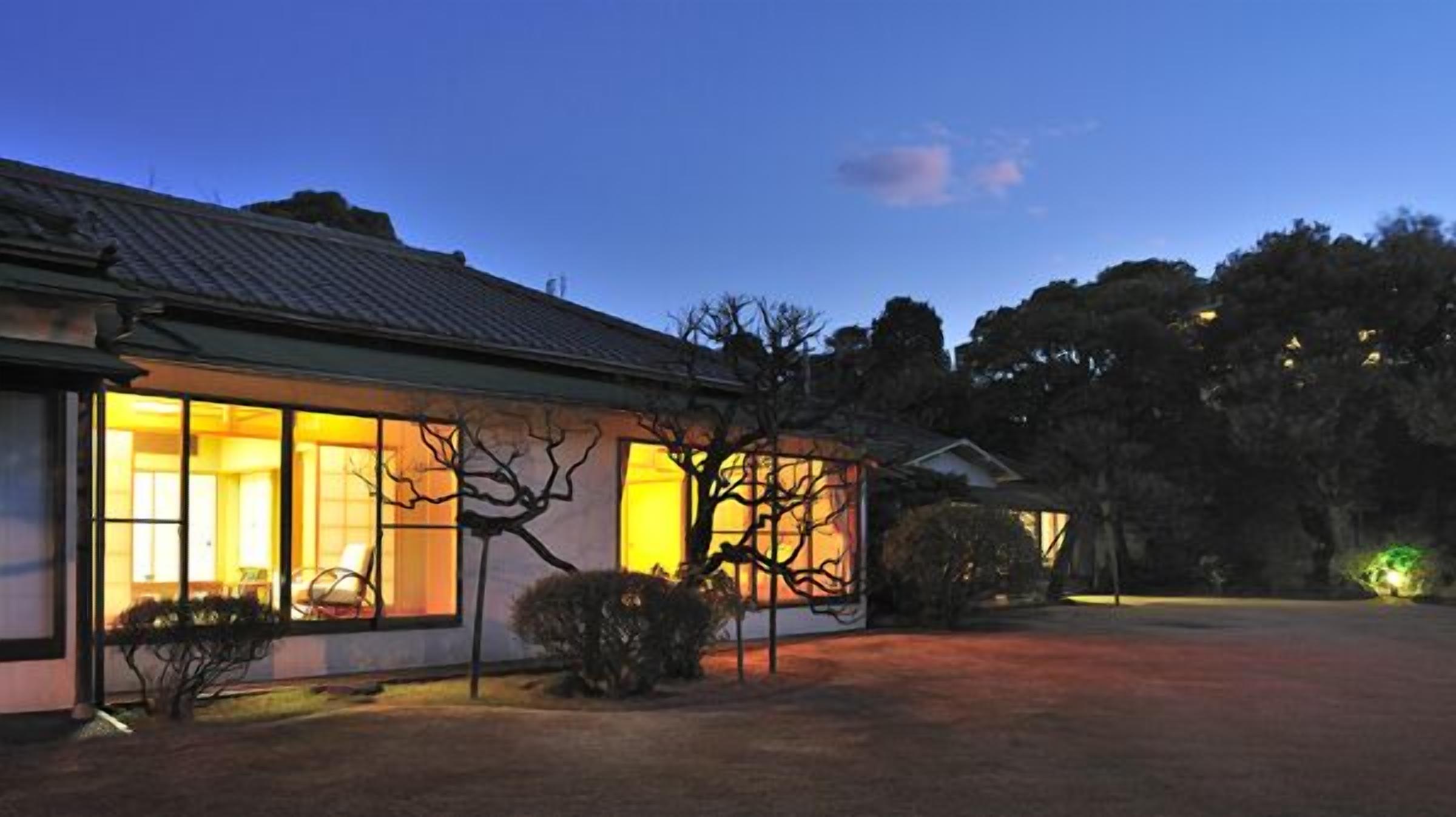 A house with large windows, a tiled roof, and a well-maintained lawn.