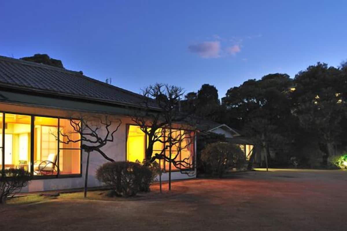 Una casa con amplias ventanas, techo de tejas y césped bien cuidado.