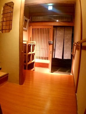 Traditional Japanese-style room with a wooden floor and sliding doors, featuring a ladder and shelf.
