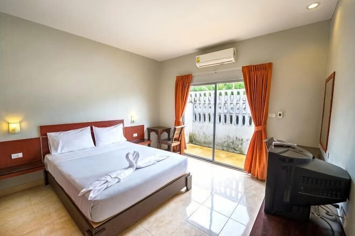 A hotel room with a bed, a TV, a desk, and a view of the outdoors.
