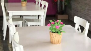 Een eetgedeelte met witte stoelen en tafels, een decoratieve muur met de tekst 'Paradise Resort', en een grote bloemstelling.