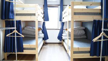 Une chambre de dortoir avec des lits superposés, un casier en métal et une fenêtre avec des rideaux.