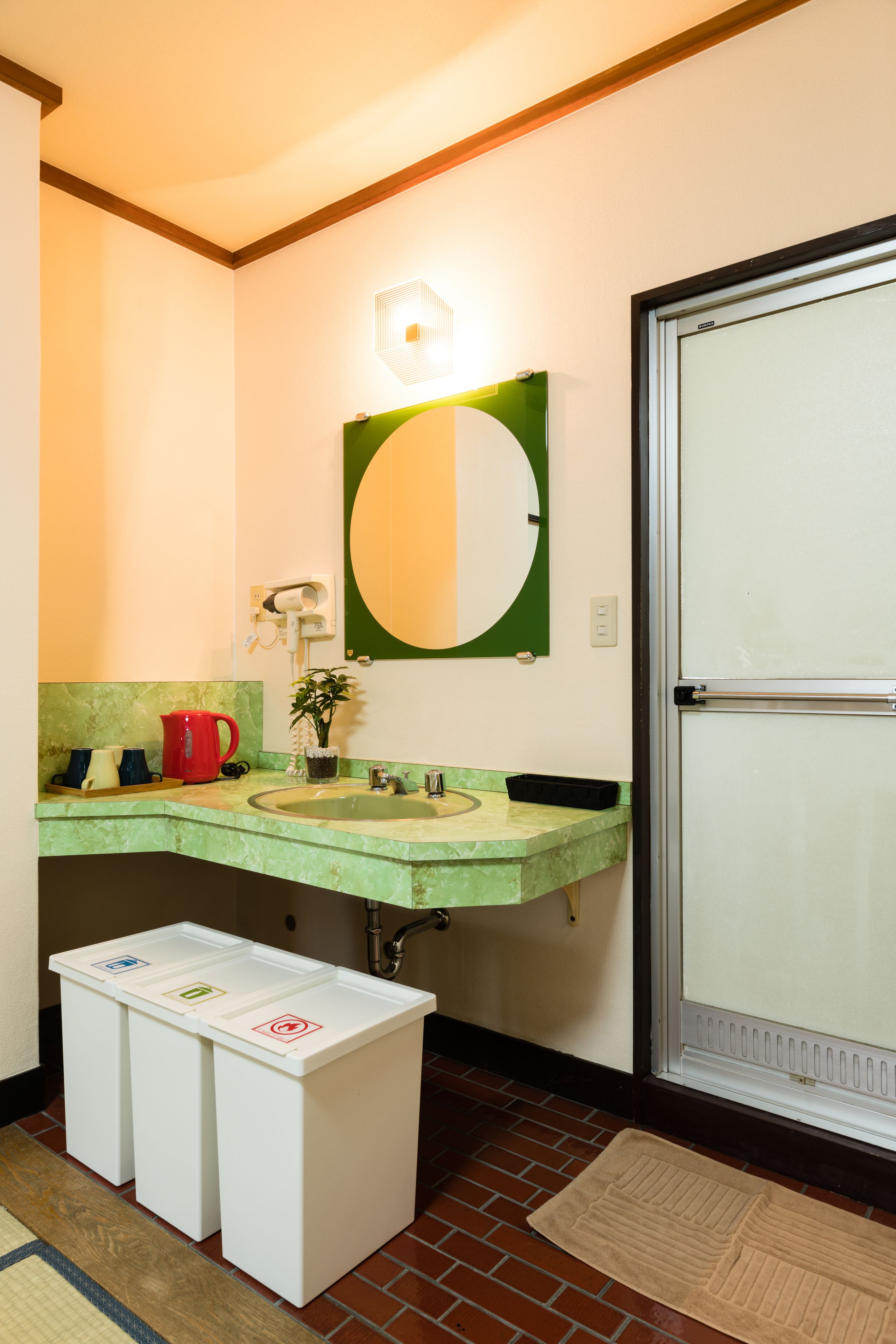 A bathroom with two sinks, a mirror, a toilet, and a trash bin.