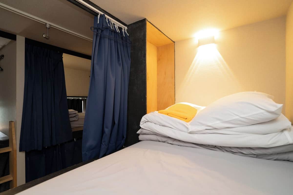 Una habitación de hotel pequeña con una cama, un armario y un espejo.