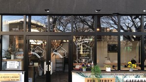 Un edificio con fachada de vidrio, un letrero para un bar de música y un letrero para una cafetería y pizzería.