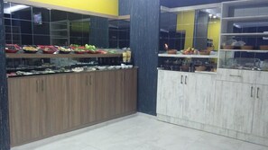 A modern kitchen with a glass display case filled with various food items, wooden cabinets, and a marble countertop.