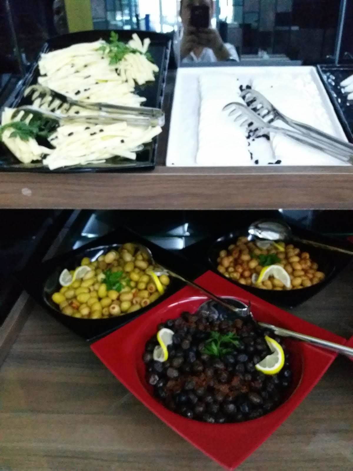 A buffet table with various dishes including sliced vegetables, beans, and a bowl of black beans garnished with lemon.