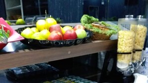 Montaje tipo bufé con diferentes alimentos, como frutas, verduras y platos ya preparados.