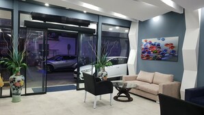 Un interior moderno con una puerta de cristal que da a un garaje, un sofá beige, una silla negra y una mesa de centro de cristal.
