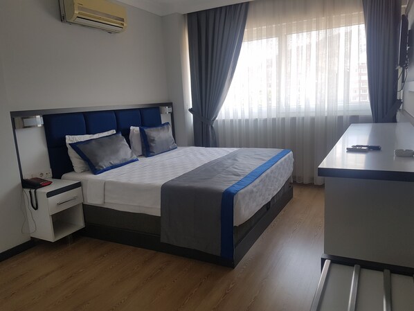 A hotel room with a bed, bedside table, and a desk with a chair.
