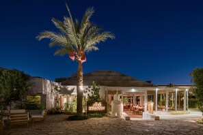 A restaurant with a palm tree, outdoor seating, and a sign that reads "SAWADI".