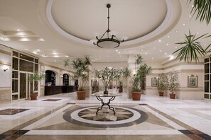 A spacious lobby with a central round table, multiple potted plants, and a chandelier. - Sindbad Club (Hurghada)