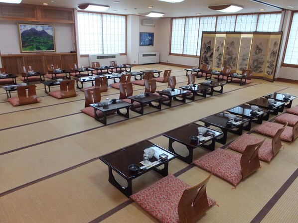 A conference room with multiple tables and chairs, large windows, and traditional decor.