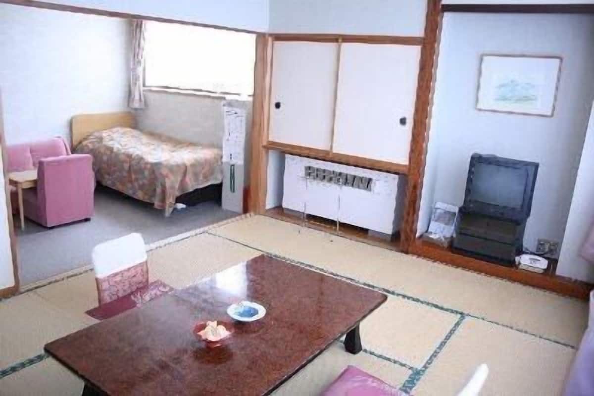 A compact room with a bed, a small table, and a television.