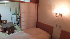 Habitación de hotel con dos camas, una mesita, una silla, un escritorio y un armario.