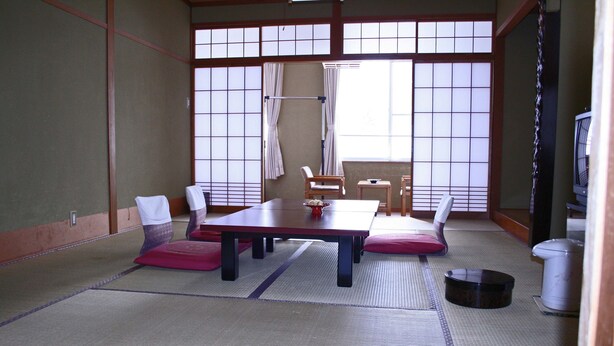 Una habitación japonesa tradicional con suelo de tatami, una mesa baja y puertas correderas shoji.