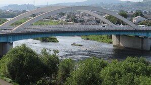 A bridge with a curved arch over a river, surrounded by greenery and a town in the background. - Tsuyama Grand Hotel (Tsuyama)
