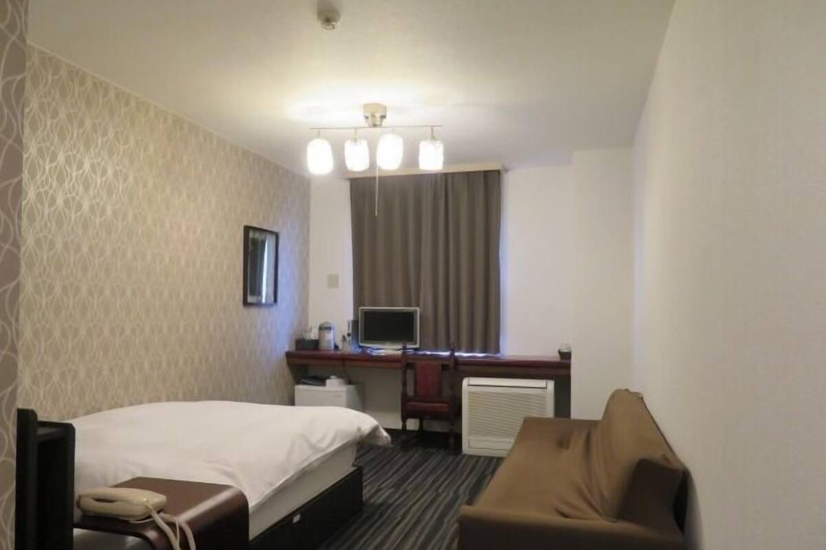 Une chambre d’hôtel comprenant un lit, un bureau avec un ordinateur, une chaise et un téléviseur.