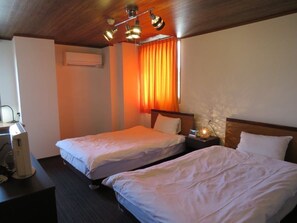 A hotel room with two beds, a desk with a computer, and a ceiling light fixture. - Tsuyama Grand Hotel (Tsuyama)