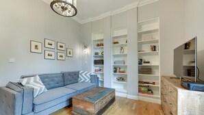 A living room with a blue sofa, a wooden coffee table, and built-in white shelving units. - Oxford Family apartment in a quiet Sopot townhouse by Lion Apartments (Sopot)