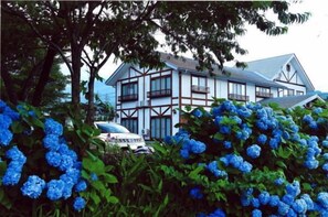 A two-story house with a gabled roof and a balcony on the upper floor. - Lodge Hitokkira (Hakuba)